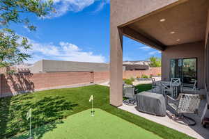 Fenced backyard featuring a patio and a putting area