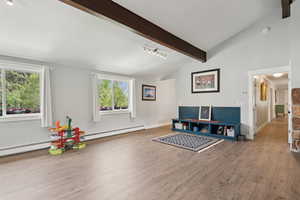 Recreation room with light wood finished floors and a baseboard radiator
