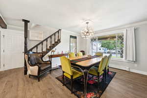Dining room featuring ornamental molding, stairs, wood finished floors, a chandelier, and a baseboard radiator