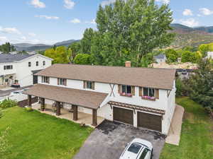 View of front of property featuring a mountain view, asphalt driveway, a front yard, a chimney, and a garage