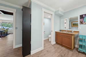 Bathroom featuring light wood finished floors, ornamental molding, and vanity