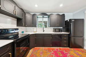 Kitchen with black appliances, tasteful backsplash, ornamental molding, and recessed lighting