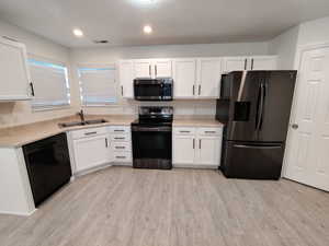 Kitchen featuring appliances with stainless steel finishes, light countertops, white cabinetry, and recessed lighting