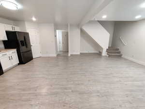 Kitchen featuring recessed lighting, white cabinetry, light countertops, light wood-style floors, and stainless steel fridge
