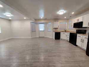 Kitchen featuring a textured ceiling, black appliances, light countertops, white cabinetry, and recessed lighting