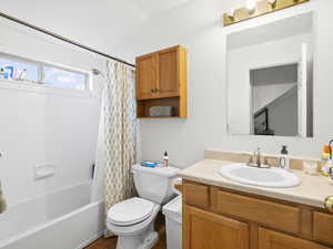 Full bath with shower / bath combination with curtain, vanity, and vaulted ceiling