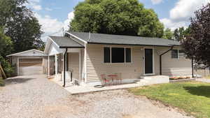 View of front of house with a shingled roof, driveway, an outbuilding, and a detached garage