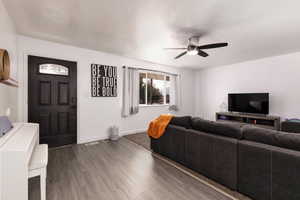 Living room featuring dark wood-style flooring and a ceiling fan
