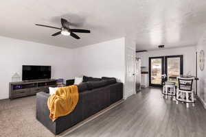 Living area with a textured ceiling, wood finished floors, and ceiling fan