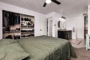 Bedroom featuring light tile patterned flooring, ceiling fan, a textured ceiling, light colored carpet, and a closet
