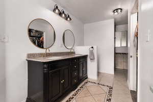 Bathroom featuring inlaid floor details, light tile patterned floors, and double vanity