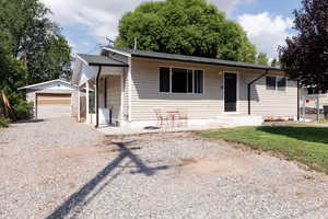 View of front facade featuring gravel driveway, an outdoor structure, and a detached garage