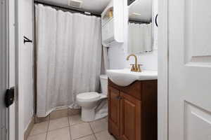 Full bathroom with light tile patterned floors, vanity, and a shower with curtain