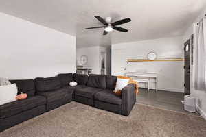Living room with carpet, a ceiling fan, and a textured ceiling