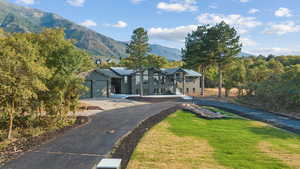 Surrounding community with a mountain view, asphalt driveway, a lawn, and a garage