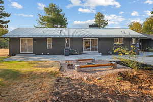 Rear view of property with a metal roof, a patio, brick siding, and a chimney