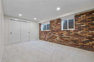 Basement featuring brick wall, carpet flooring, and recessed lighting