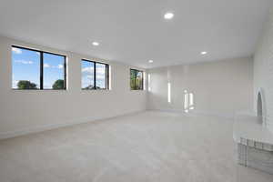 Unfurnished room featuring a brick fireplace, recessed lighting, and light carpet