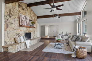 Living room featuring a stone fireplace, dark wood finished floors, ceiling fan, beamed ceiling, and high vaulted ceiling
