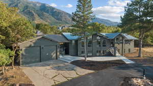 View of front of house featuring a metal roof, brick siding, concrete driveway, a mountain view, and an attached garage