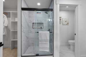 Full bath with a marble finish shower, light marble finish floors, and recessed lighting