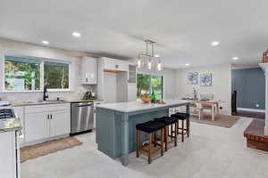 Kitchen with white cabinetry, tasteful backsplash, a breakfast bar, dishwasher, and recessed lighting