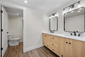 Bathroom with wood tiled floors, double vanity, and recessed lighting