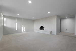 Unfurnished living room with recessed lighting, a fireplace, and light colored carpet