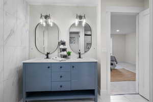 Ensuite bathroom featuring double vanity, light tile patterned flooring, and tile walls