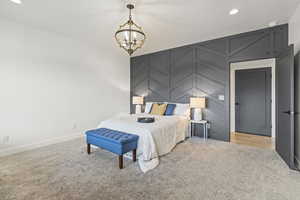 Bedroom with recessed lighting, light colored carpet, a chandelier, and an accent wall