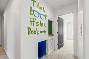 Corridor featuring light carpet and baseboards