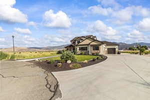 Craftsman-style home featuring a mountain view, stone siding, curved driveway, stucco siding, and an attached garage