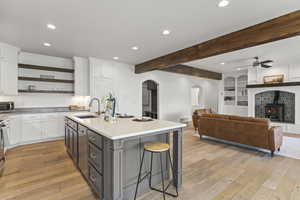Kitchen featuring recessed lighting, white cabinets, a breakfast bar, beam ceiling, and light wood-style flooring