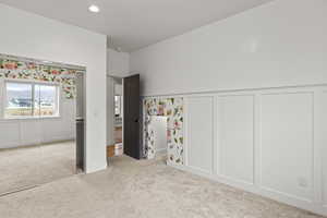 Unfurnished bedroom with a wainscoted wall, a decorative wall, carpet flooring, recessed lighting, and a closet