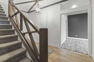 Staircase with wood-type flooring and a chandelier
