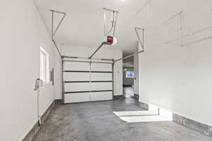 Garage featuring a garage door opener and baseboards