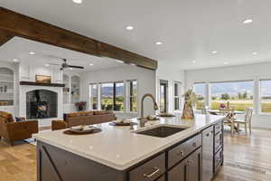 Kitchen featuring beamed ceiling, a wood stove, light wood-style flooring, recessed lighting, and light stone counters