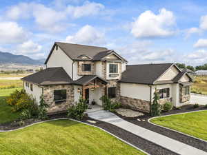 View of front facade featuring a front lawn, stone siding, and stucco siding