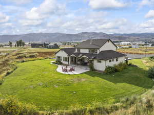 Back of property with a patio area, stucco siding, a mountain view, and a lawn