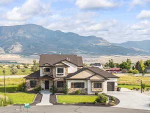 View of front of property with concrete driveway, stone siding, a mountain view, and an attached garage