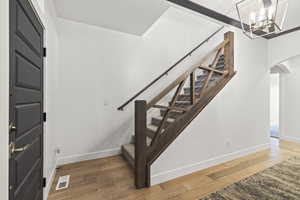Stairway featuring hardwood / wood-style flooring, arched walkways, and a chandelier