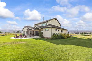 Back of house featuring a mountain view, a patio, stucco siding, and a lawn