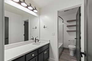 Bathroom featuring vanity, shower / tub combination, and dark wood-style floors