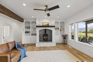 Living room with light wood-type flooring, a wood stove, recessed lighting, arched walkways, and a ceiling fan