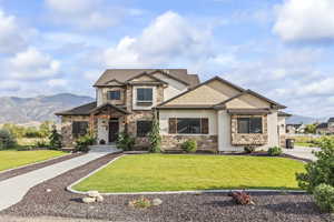 Craftsman-style house with a front lawn, a mountain view, and stone siding