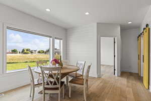 Dining space with a barn door, recessed lighting, and light wood-style flooring