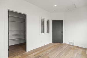 Unfurnished bedroom featuring attic access, light wood-style floors, recessed lighting, and a walk in closet