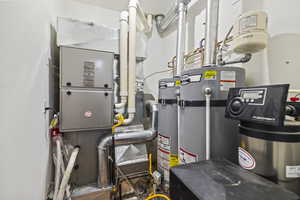 Utility room featuring heating unit and strapped water heater