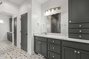 Full bath featuring a stall shower, double vanity, and light tile patterned floors