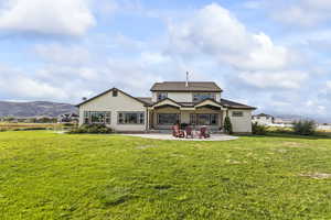 Rear view of property featuring a mountain view, stucco siding, a patio area, and a yard